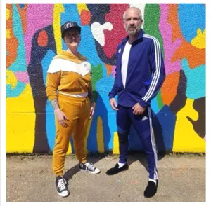 A photo of Ben Alway and Madi Rawson in front of the mural by Jean Paul Langlois