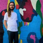 A photo of Jake Vanderwerf in front of the mural by Jean Paul Langlois.