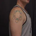 A photo of the crest tattoo on the shoulder after one treatment, 14 weeks later.