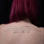 A photo of the script tattoo on the back of the shoulders, after one treatment, 13 weeks later